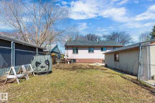 Expansive backyard featuring a partial chain-link fence, mature trees, and a detached structure with stucco siding - 10531 128 Avenue, Edmonton, AB - Outdoor