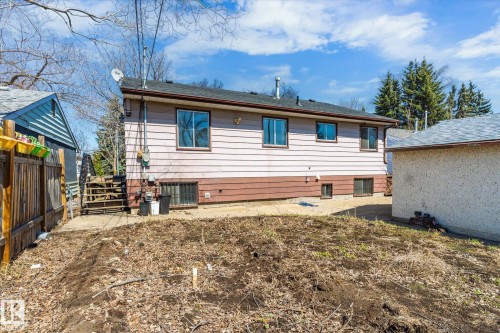 Rear exterior featuring vinyl siding in a two-tone finish, multiple windows, and a dark shingle roof - 10531 128 Avenue, Edmonton, AB - Outdoor