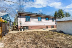 Rear exterior featuring vinyl siding in a two-tone finish, multiple windows, and a dark shingle roof - 