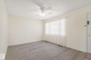 Open concept living space featuring wood-finish flooring, a ceiling fan with integrated lighting, and a large window with privacy coverings - 10531 128 Avenue, Edmonton, AB  - Indoor Photo Showing Other Room 