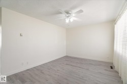 Interior room featuring light-toned walls, wood-finish flooring, and white baseboards - 