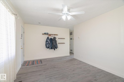 Entry area featuring wood-finish flooring, a ceiling fan with integrated lighting, and neutral wall tones - 10531 128 Avenue, Edmonton, AB - Indoor Photo Showing Other Room