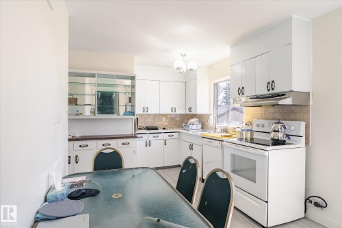 Bright kitchen featuring white cabinetry, a built-in range hood, and tile backsplash - 10531 128 Avenue, Edmonton, AB - Indoor Photo Showing Kitchen