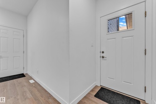 Entry foyer featuring a paneled door with an upper window, wood-finish flooring, and crisp white trim - 41 603 Orchards Boulevard, Edmonton, AB - Indoor Photo Showing Other Room