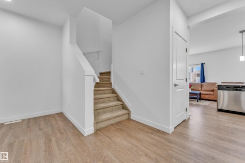 Warm wood-finish flooring extending from the entryway - 41 603 Orchards Boulevard, Edmonton, AB - Indoor Photo Showing Other Room