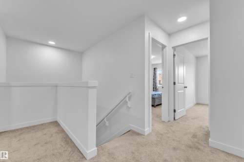 Carpeted hallway with a white painted railing and recessed lighting - 41 603 Orchards Boulevard, Edmonton, AB - Indoor Photo Showing Other Room