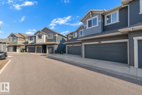 Multi-unit residential structures featuring dark siding, light trim, and integrated garage doors - 41 603 Orchards Boulevard, Edmonton, AB - Outdoor With Facade