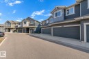 Multi-unit residential structures featuring dark siding, light trim, and integrated garage doors - 41 603 Orchards Boulevard, Edmonton, AB  - Outdoor With Facade 