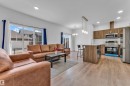 Open-concept living area featuring wood-finish flooring, recessed lighting, and a sliding glass door - 41 603 Orchards Boulevard, Edmonton, AB  - Indoor 