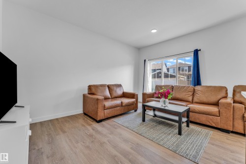 Open-concept living space with wood-finish flooring, recessed lighting, and a large window - 41 603 Orchards Boulevard, Edmonton, AB - Indoor Photo Showing Living Room