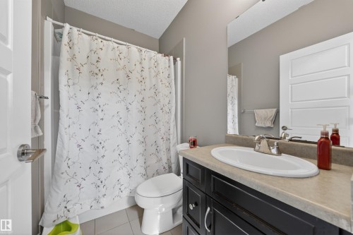 Bathroom featuring a dark wood-finish vanity with an undermount sink, a neutral countertop, and a large wall-mounted mirror - 3639 15A Street, Edmonton, AB - Indoor Photo Showing Bathroom