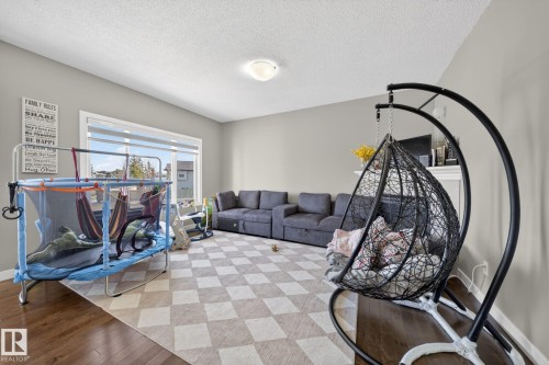 Spacious interior featuring neutral wall tones, large windows, wood-finish flooring, and a ceiling-mounted light fixture - 3639 15A Street, Edmonton, AB - Indoor