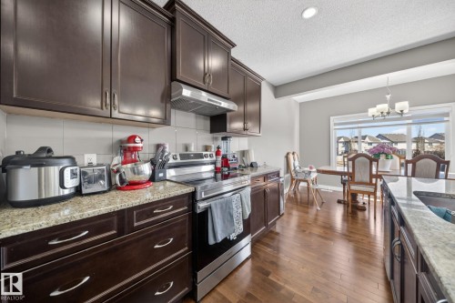 Expansive kitchen featuring wood-finish flooring, dark wood cabinetry, and a granite countertop - 3639 15A Street, Edmonton, AB - Indoor Photo Showing Kitchen