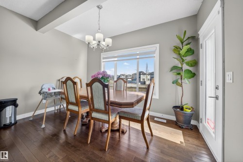Spacious dining area featuring wood-finish flooring, a large window, a ceiling-mounted chandelier, and direct access to an exterior door - 3639 15A Street, Edmonton, AB - Indoor Photo Showing Dining Room