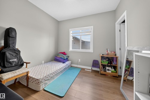 Bright room with neutral wall tones, wood-finish flooring, and a window featuring horizontal blinds - 3639 15A Street, Edmonton, AB - Indoor Photo Showing Bedroom