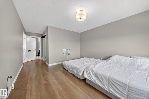 Room featuring wood-finish flooring, light grey painted walls, and a white popcorn ceiling - 3639 15A Street, Edmonton, AB - Indoor Photo Showing Bedroom