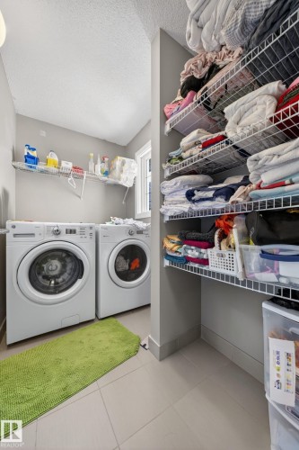Dedicated laundry space featuring a side-by-side washer and dryer, tile flooring, and integrated wire shelving for abundant storage - 3639 15A Street, Edmonton, AB - Indoor Photo Showing Laundry Room