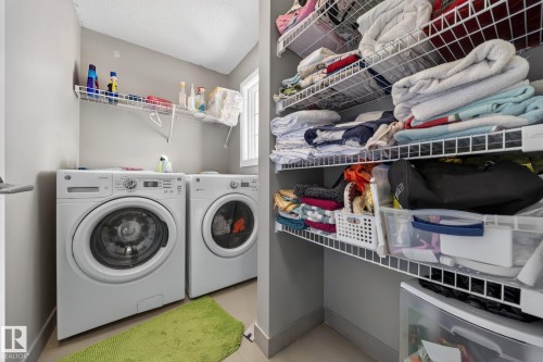 Dedicated laundry area featuring a front-loading washer and dryer, upper wire shelving, and neutral wall tones - 3639 15A Street, Edmonton, AB - Indoor Photo Showing Laundry Room