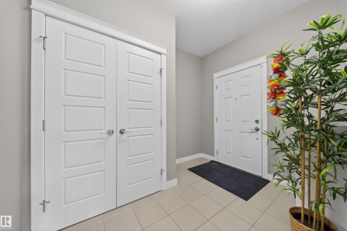 Entryway featuring light-toned tile flooring, a white paneled entry door, and a white bi-fold closet door with satin nickel hardware - 3639 15A Street, Edmonton, AB - Indoor Photo Showing Other Room