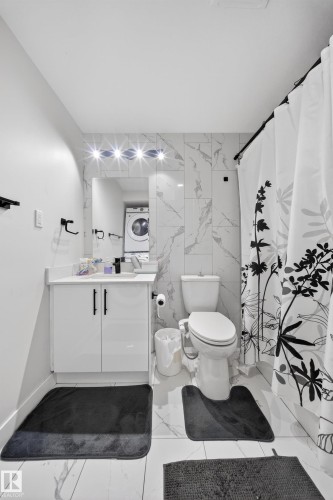 Bathroom featuring a white vanity with black hardware, white countertop, and integrated sink - 3639 15A Street, Edmonton, AB - Indoor Photo Showing Bathroom