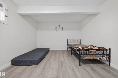 Spacious room with light-toned wood-finish flooring, white baseboards, and a window providing natural illumination - 3639 15A Street, Edmonton, AB - Indoor Photo Showing Bedroom