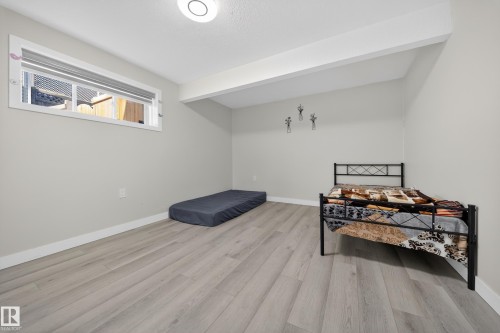 Spacious room featuring light gray walls, wood-finish flooring, white baseboards, and a recessed window with a privacy blind - 3639 15A Street, Edmonton, AB - Indoor