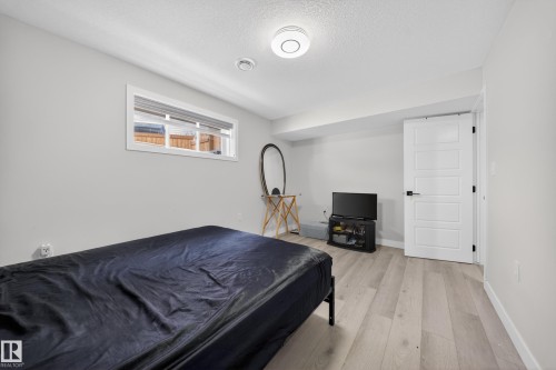 Room featuring light wood-finish flooring, a contemporary white door with black hardware, a recessed window, and white walls - 3639 15A Street, Edmonton, AB - Indoor Photo Showing Bedroom
