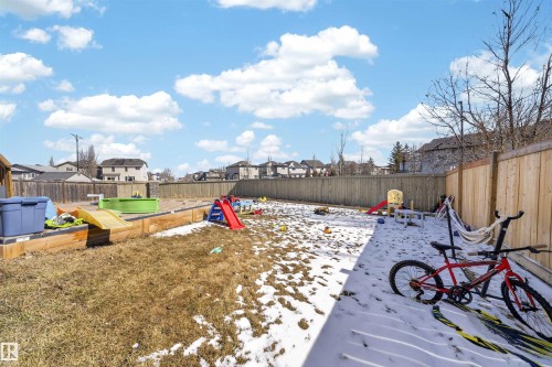 Spacious rear yard featuring a wooden privacy fence, raised garden beds, and a combination of grass and snow cover - 3639 15A Street, Edmonton, AB - Outdoor With Backyard