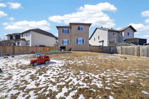 Expansive backyard featuring a partial wooden fence, a brown-sided multi-story home with multiple windows, and a lower-level deck - 3639 15A Street, Edmonton, AB - Outdoor