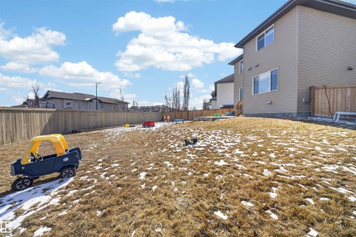 Expansive backyard featuring a partial wooden fence, sloped terrain, and a beige vinyl-sided exterior - 3639 15A Street, Edmonton, AB - Outdoor