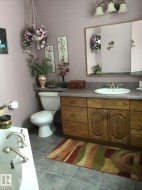 Bathroom featuring a light-colored vanity with a built-in sink, a wall-mounted mirror, and a three-light fixture overhead - 