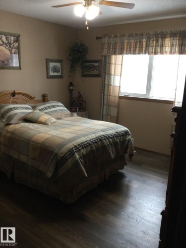 Spacious room featuring wood-finish flooring, a ceiling fan with integrated lighting, and a window with wood trim - 123064 Hwy 45, Rural Two Hills County, AB 