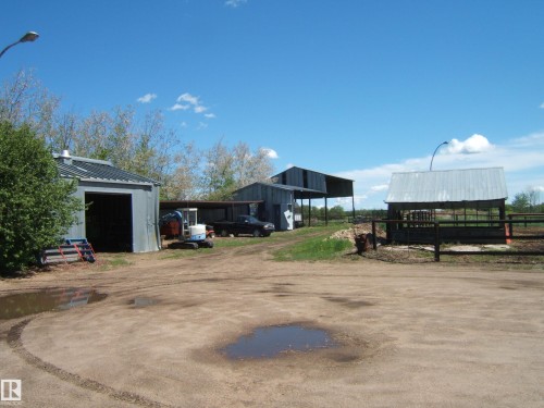 A collection of functional outbuildings including two metal-sided structures with roll-up doors and a barn-style building with an open-air design - 123064 Hwy 45, Rural Two Hills County, AB 