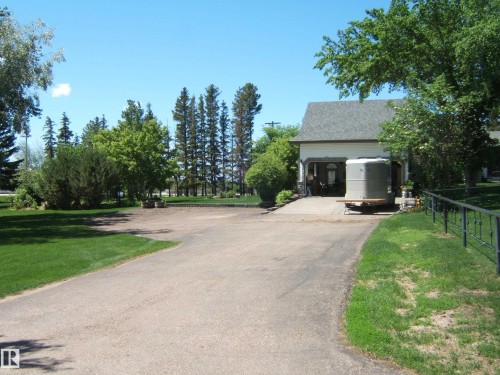 Asphalt driveway leading to a residence with a light-colored stucco exterior and a dark shingled roof - 123064 Hwy 45, Rural Two Hills County, AB 