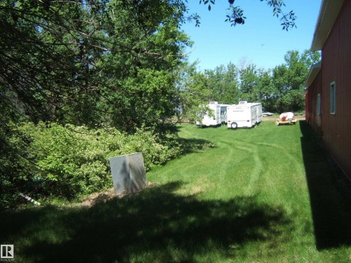 Expansive green lawn bordering a red-sided structure - 123064 Hwy 45, Rural Two Hills County, AB 