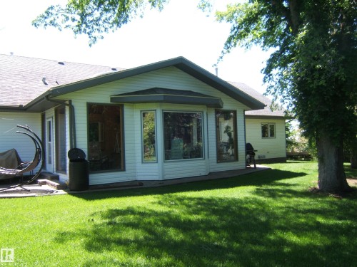 Rear exterior featuring a sunroom addition with large bay windows and white siding - 123064 Hwy 45, Rural Two Hills County, AB 