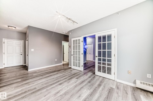 Empty room featuring french doors, light wood-style flooring, and a baseboard radiator - 507 11716 100 Avenue, Edmonton, AB - Indoor Photo Showing Other Room