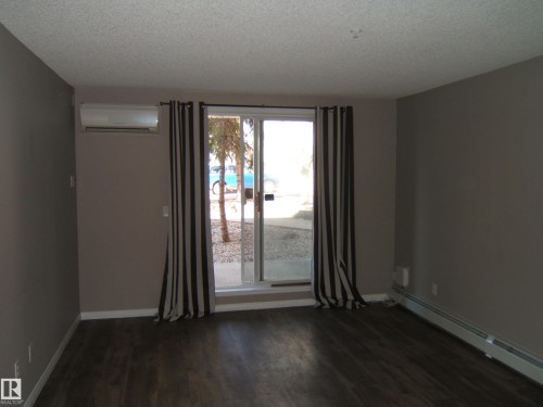 Interior living space featuring dark wood-finish flooring, neutral-toned walls, and white baseboards - 105 11214 80 Street, Edmonton, AB - Indoor Photo Showing Other Room