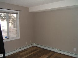 Room featuring wood-finish flooring, a window with white trim, and baseboard heating - 