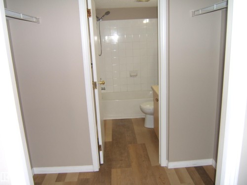 Bathroom featuring a white subway tile surround, a standard bathtub with shower, and a light wood-finish vanity - 105 11214 80 Street, Edmonton, AB - Indoor Photo Showing Bathroom