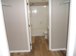 Bathroom featuring a white subway tile surround, a standard bathtub with shower, and a light wood-finish vanity - 