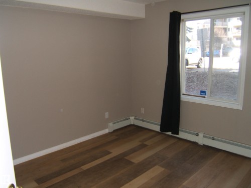Room featuring wood-finish flooring, neutral wall tones, and white trim - 105 11214 80 Street, Edmonton, AB - Indoor Photo Showing Other Room