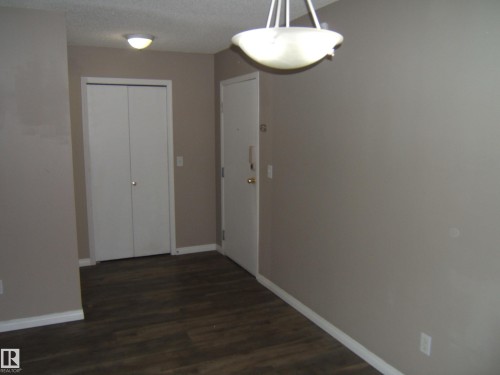 Entry area featuring wood-finish flooring, neutral wall paint, and white trim - 105 11214 80 Street, Edmonton, AB - Indoor Photo Showing Other Room