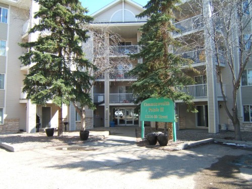 Multi-level condominium building featuring a neutral-toned siding exterior, stone veneer accents, and multiple private balconies with white railings - 105 11214 80 Street, Edmonton, AB - Outdoor With Facade