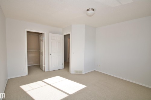 Neutral-toned carpeted room featuring white walls and baseboards - 11 230 Edwards Drive, Edmonton, AB - Indoor