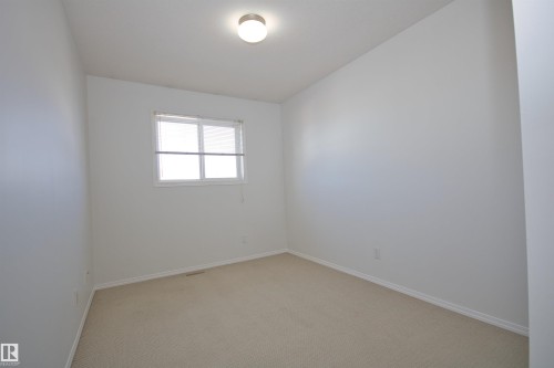 Neutral wall finishes and light-toned carpeting create a bright interior - 11 230 Edwards Drive, Edmonton, AB - Indoor Photo Showing Other Room