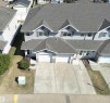 Light gray siding exterior with stone accents and multiple attached single-car garages - 11 230 Edwards Drive, Edmonton, AB  - Outdoor 