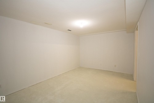 Spacious room featuring light-toned carpeting, white painted walls, and a flush-mount ceiling light fixture - 11 230 Edwards Drive, Edmonton, AB - Indoor Photo Showing Other Room