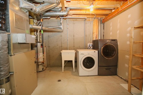 Utility room featuring a utility sink, concrete flooring, and exposed ceiling joists - 11 230 Edwards Drive, Edmonton, AB - Indoor Photo Showing Laundry Room