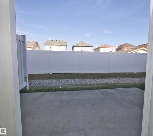 Concrete patio area with a white vinyl privacy fence - 11 230 Edwards Drive, Edmonton, AB - Outdoor